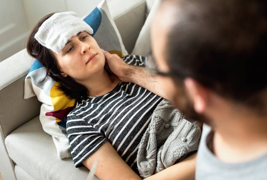 zena sa temperaturom sa mokrom krpom na glavi